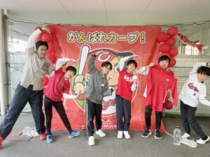 サイン入りの横断幕の前にカープポーズを決める子どもたち。